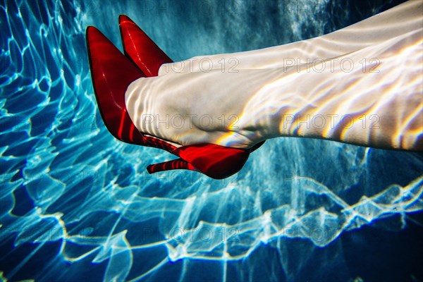 Legs of woman wearing high heels in swimming pool