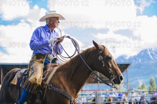 Older Caucasian cowboy riding horse at rodeo