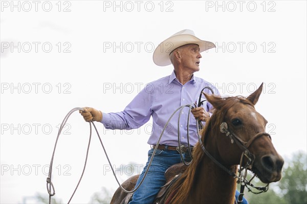 Caucasian cowboy riding horse in rodeo