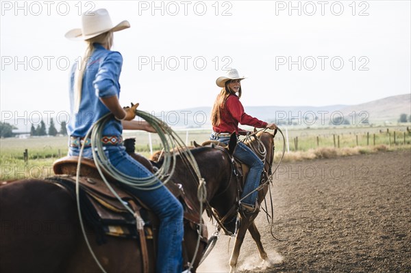 Caucasian cowgirls riding horses on ranch