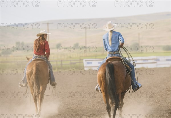 Caucasian cowgirls riding horses on ranch