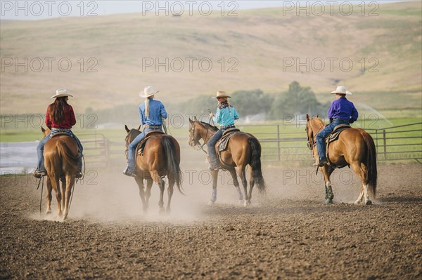 Cowgirls and cowboy riding horses on ranch