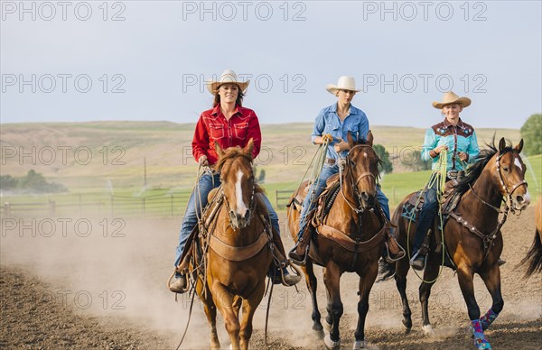 Cowgirls riding horses on ranch