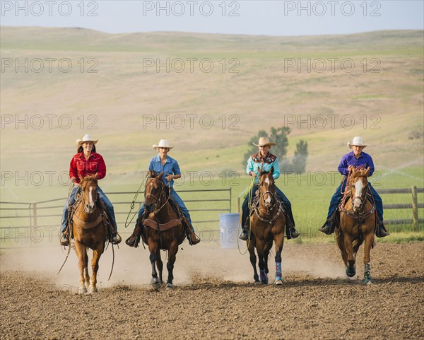 Cowgirls and cowboy riding horses on ranch