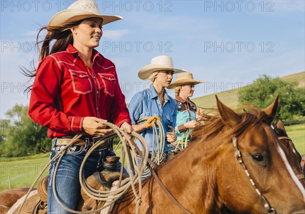 Cowgirls riding horses on ranch