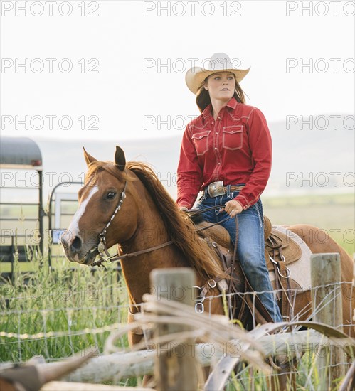 Caucasian cowgirl riding horse on ranch