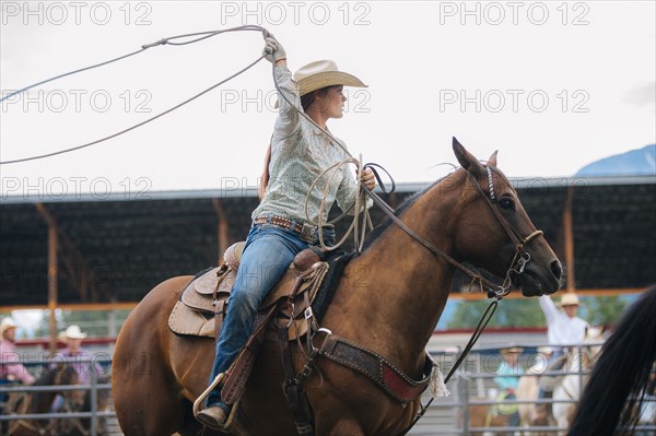 Caucasian cowgirl twirling lasso in rodeo