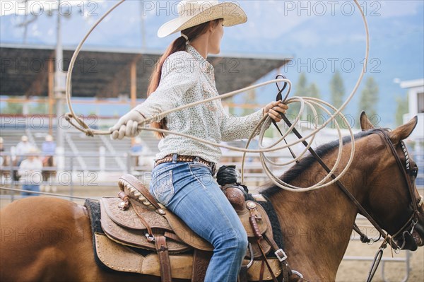 Caucasian cowgirl twirling lasso in rodeo