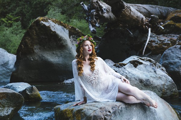 Caucasian woman wearing flower crown on rock at river