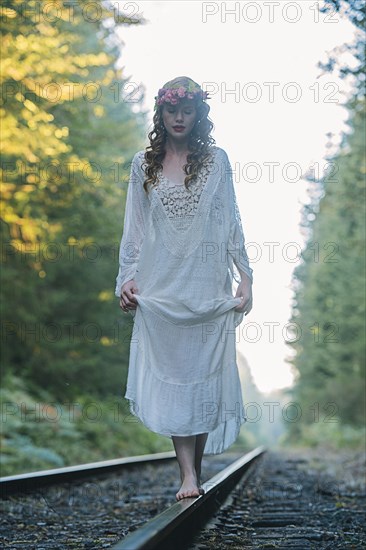 Caucasian woman balancing on train tracks in forest