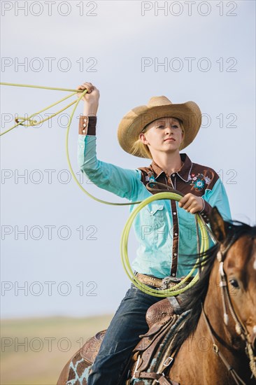 Caucasian cowgirl throwing lasso on horseback