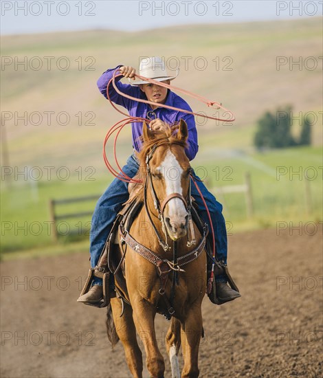 Cowboy throwing lasso on horseback