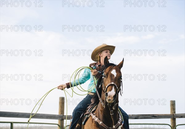 Caucasian cowgirl throwing lasso on horseback