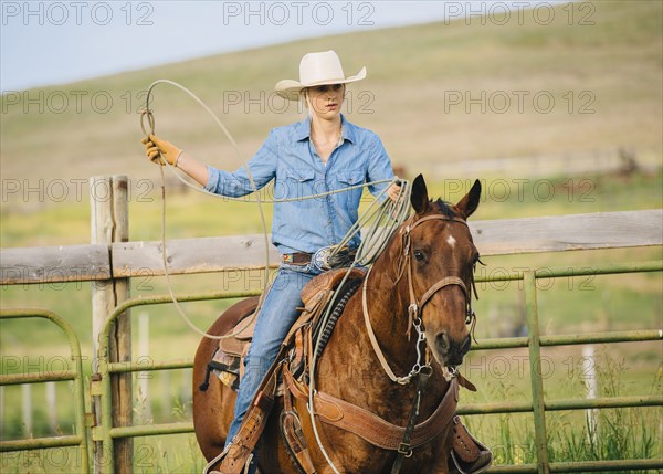 Caucasian cowgirl throwing lasso on horseback