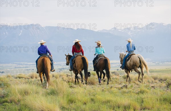 Cowboy and cowgirls riding horseback on ranch