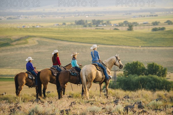 Cowboy and cowgirls on horseback admiring rural landscape