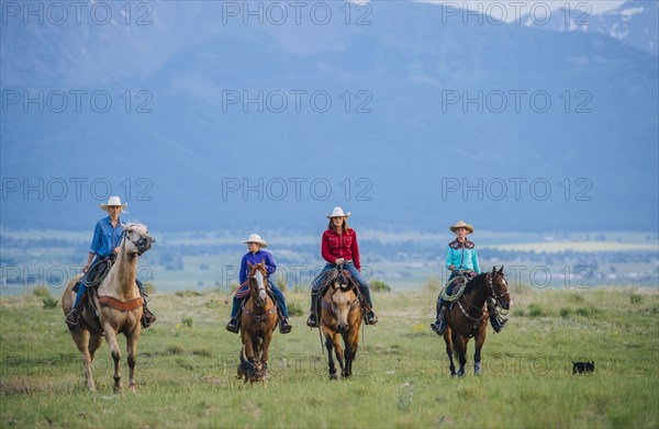 Cowboy and cowgirls riding horseback on ranch