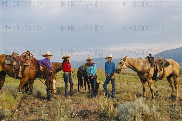 Cowboy and cowgirls with horses on ranch