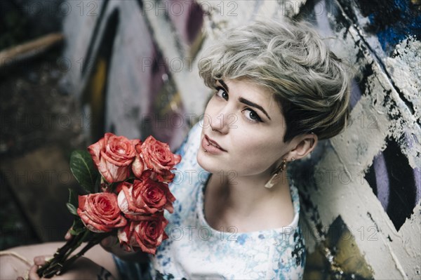 Caucasian woman at graffiti wall holding flowers