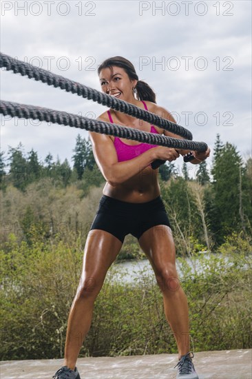 Mixed Race woman working out with heavy ropes