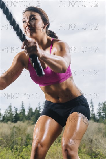 Mixed Race woman working out with heavy ropes