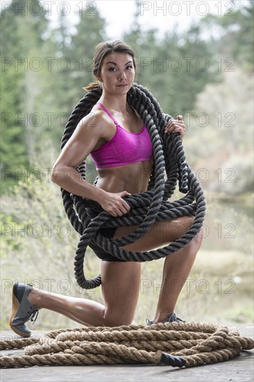 Kneeling Mixed Race woman carrying heavy ropes