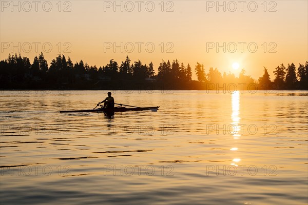 Silhouette of Caucasian man rowing at sunset