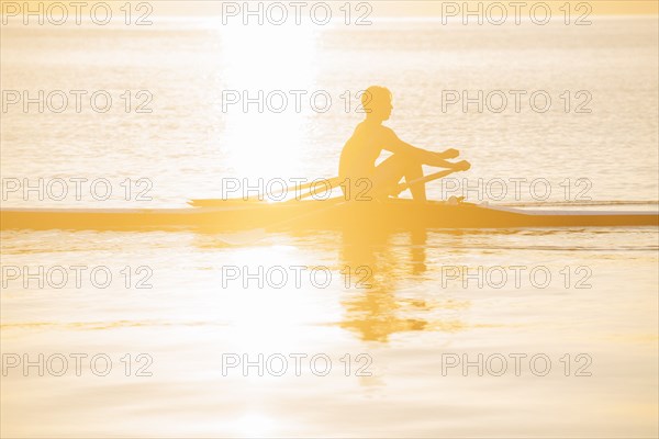 Silhouette of Caucasian man rowing on lake