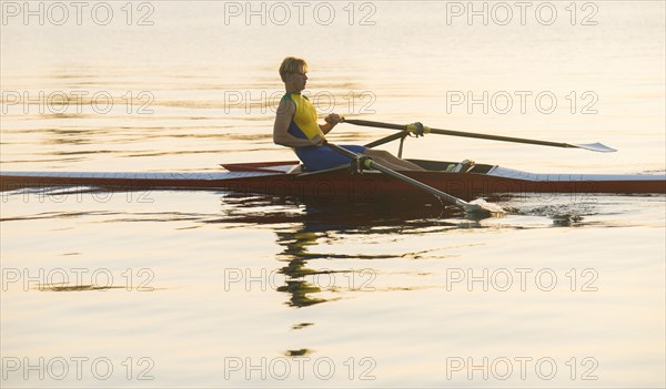 Caucasian man rowing on lake