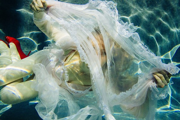 Caucasian woman wearing dress swimming underwater