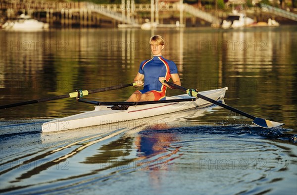 Caucasian man rowing on river