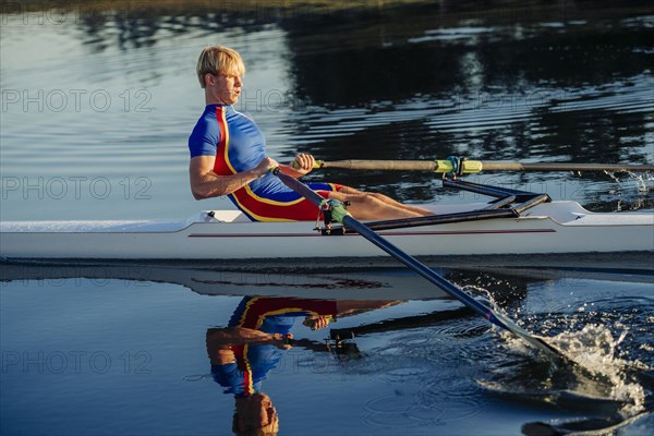 Caucasian man rowing on river