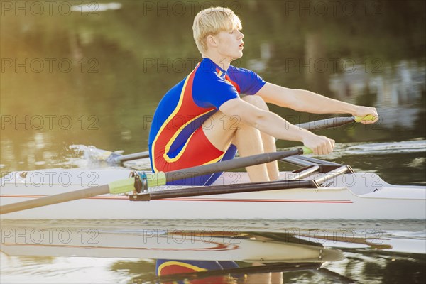 Caucasian man rowing on river