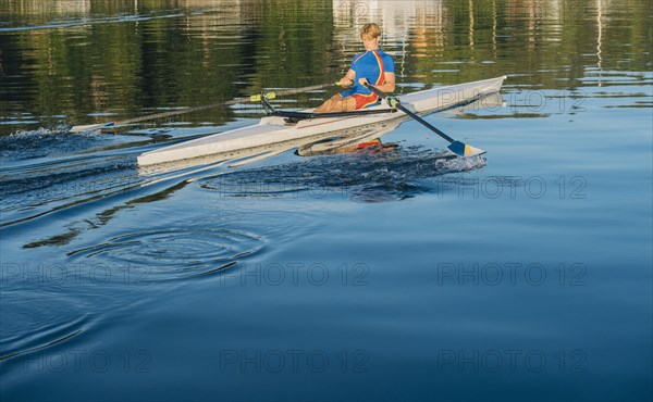 Caucasian man rowing on river