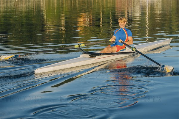 Caucasian man rowing on river