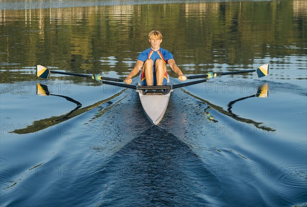 Caucasian man rowing on river