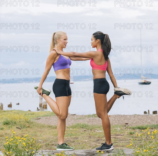 Women stretching legs near lake