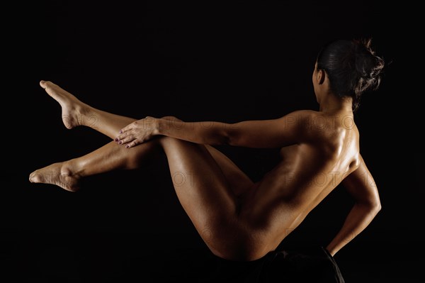 Naked muscular Mixed Race woman lifting legs