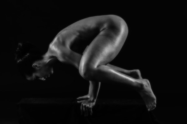 Naked muscular Mixed Race woman balancing on hands