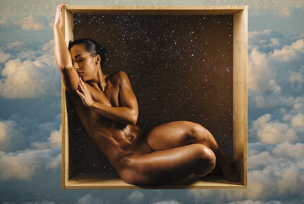 Muscular Mixed Race woman covering breasts in box