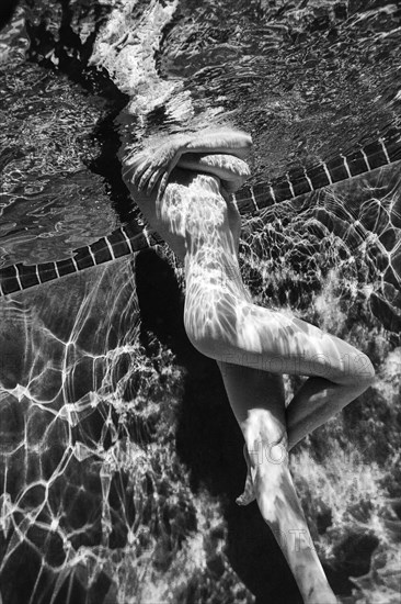 Naked Caucasian woman swimming underwater