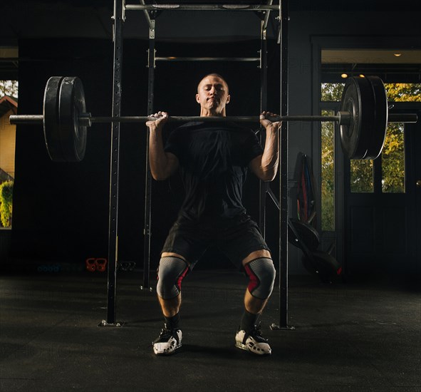 Man lifting heavy barbell in gymnasium