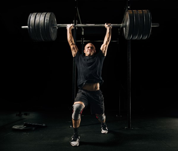 Man lifting heavy barbell in gymnasium