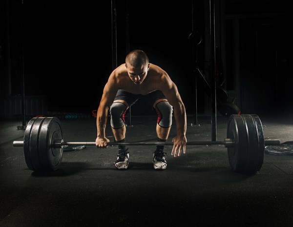 Man lifting heavy barbell in gymnasium