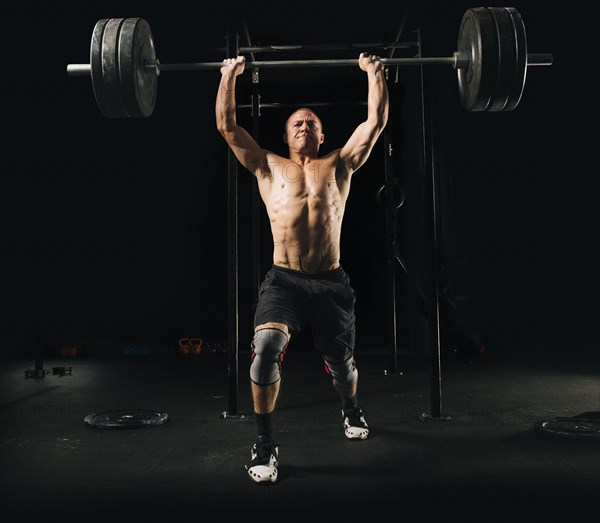 Man lifting heavy barbell in gymnasium