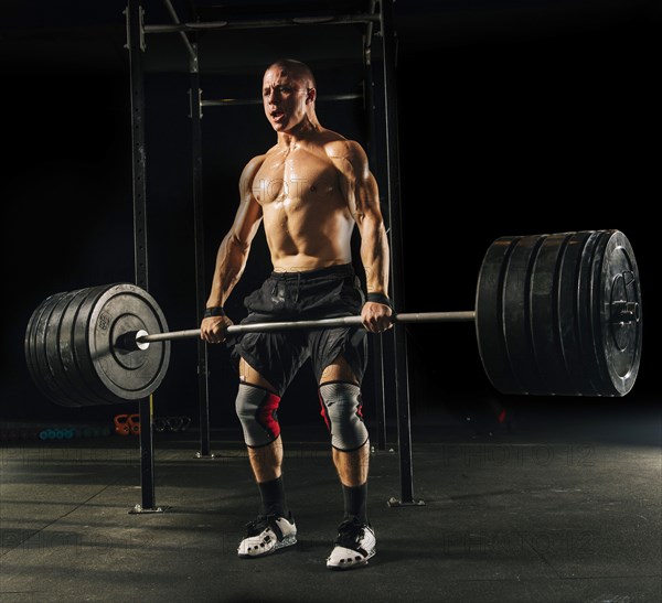 Man lifting heavy barbell in gymnasium