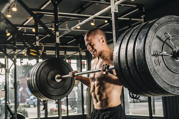 Man lifting heavy barbell in gymnasium