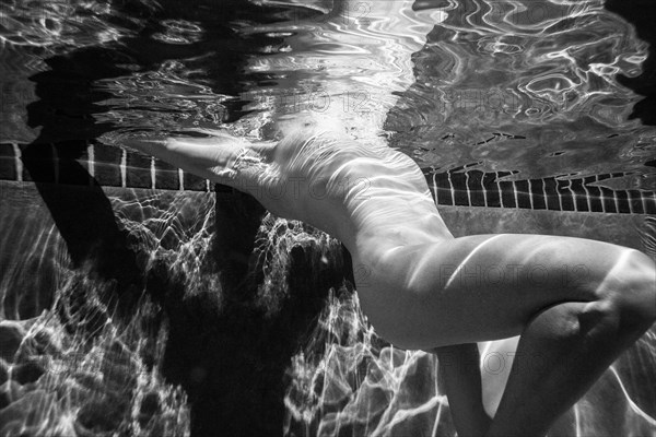 Naked Caucasian woman swimming underwater