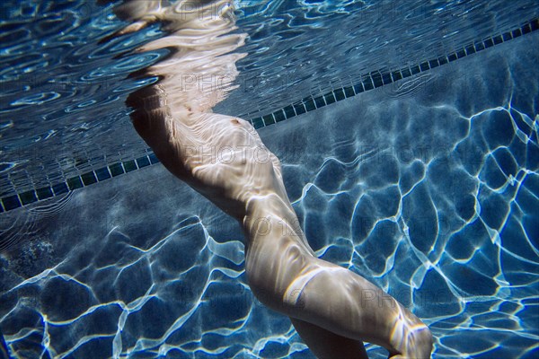 Naked Caucasian woman swimming underwater