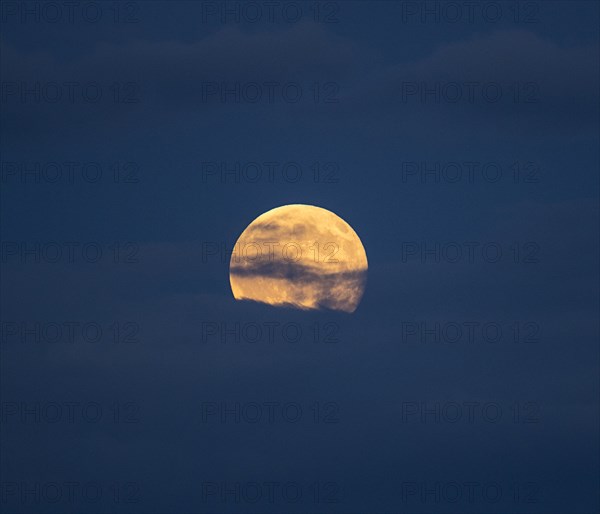 Clouds in sky in front of full moon